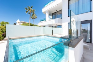 Ein moderner Pool mit klarem, blauem Wasser, umgeben von einem weißen Gebäude mit Balkonen und Glasgeländern.