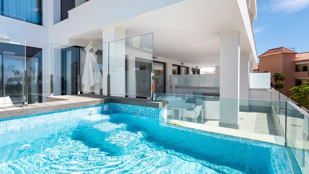 A modern outdoor swimming pool with glass railings, a white interior, and a clear blue sky. - Santa Barbara Heights IV CLC - Luxury, private plunge pool (Mijas Costa)