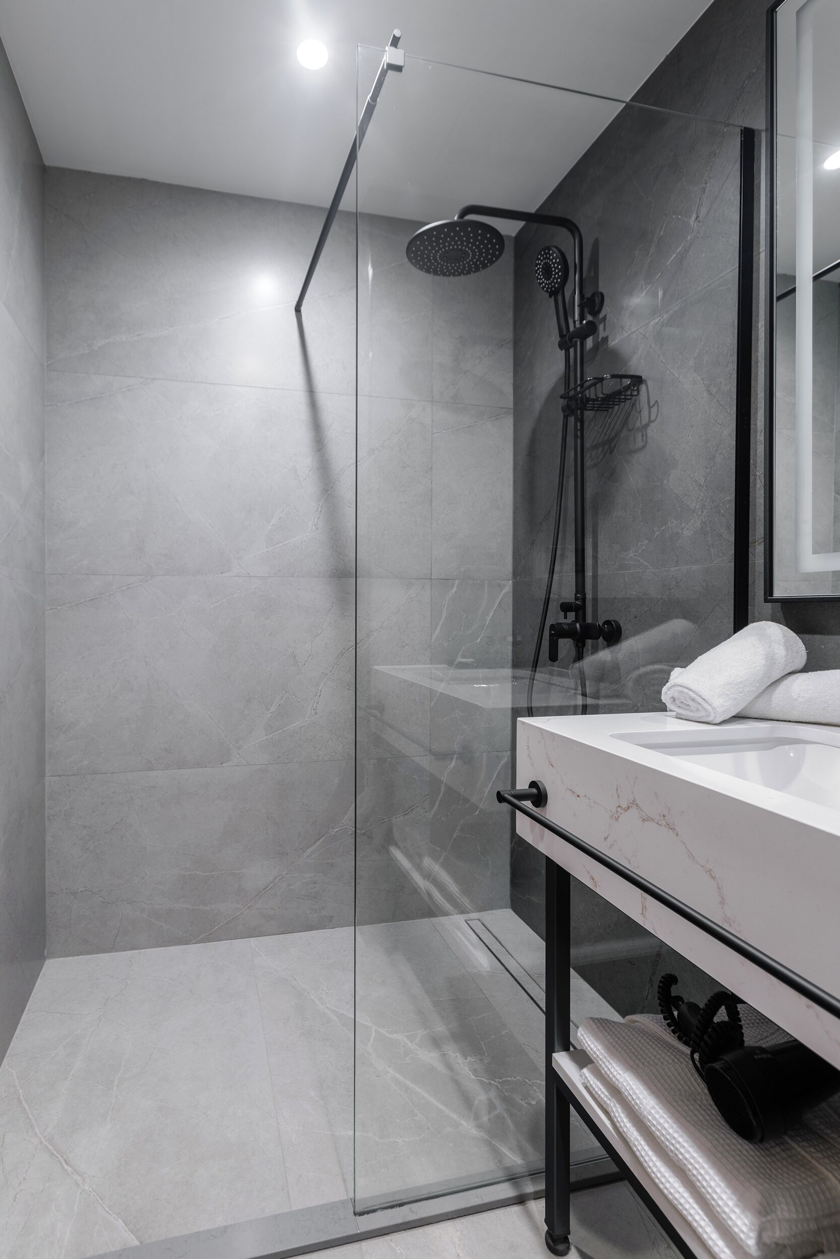 A modern bathroom with a glass-enclosed shower, a marble sink, and a towel rack.