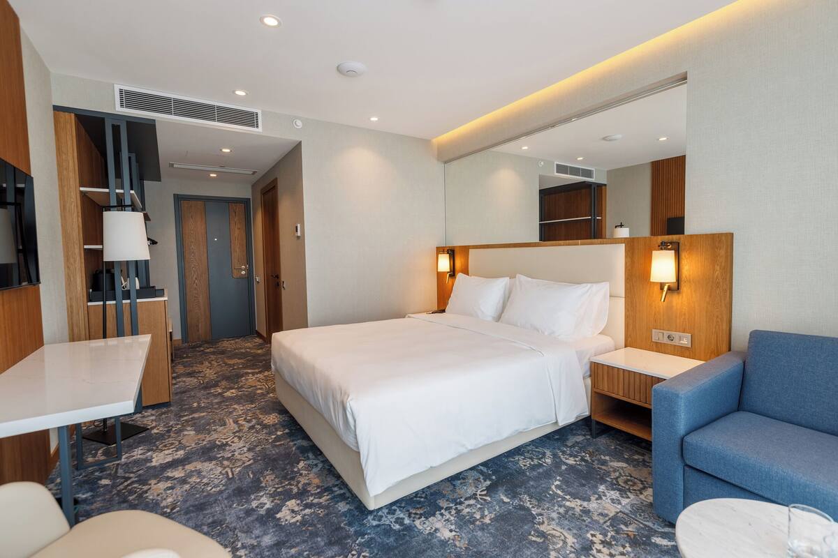 Une chambre d’hôtel moderne avec un grand lit, un bureau, une chaise et une petite table.