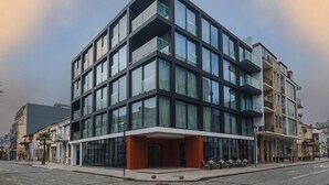 Ein modernes Gebäude mit mehreren Stockwerken, großen Fenstern und einem flachen Dach.