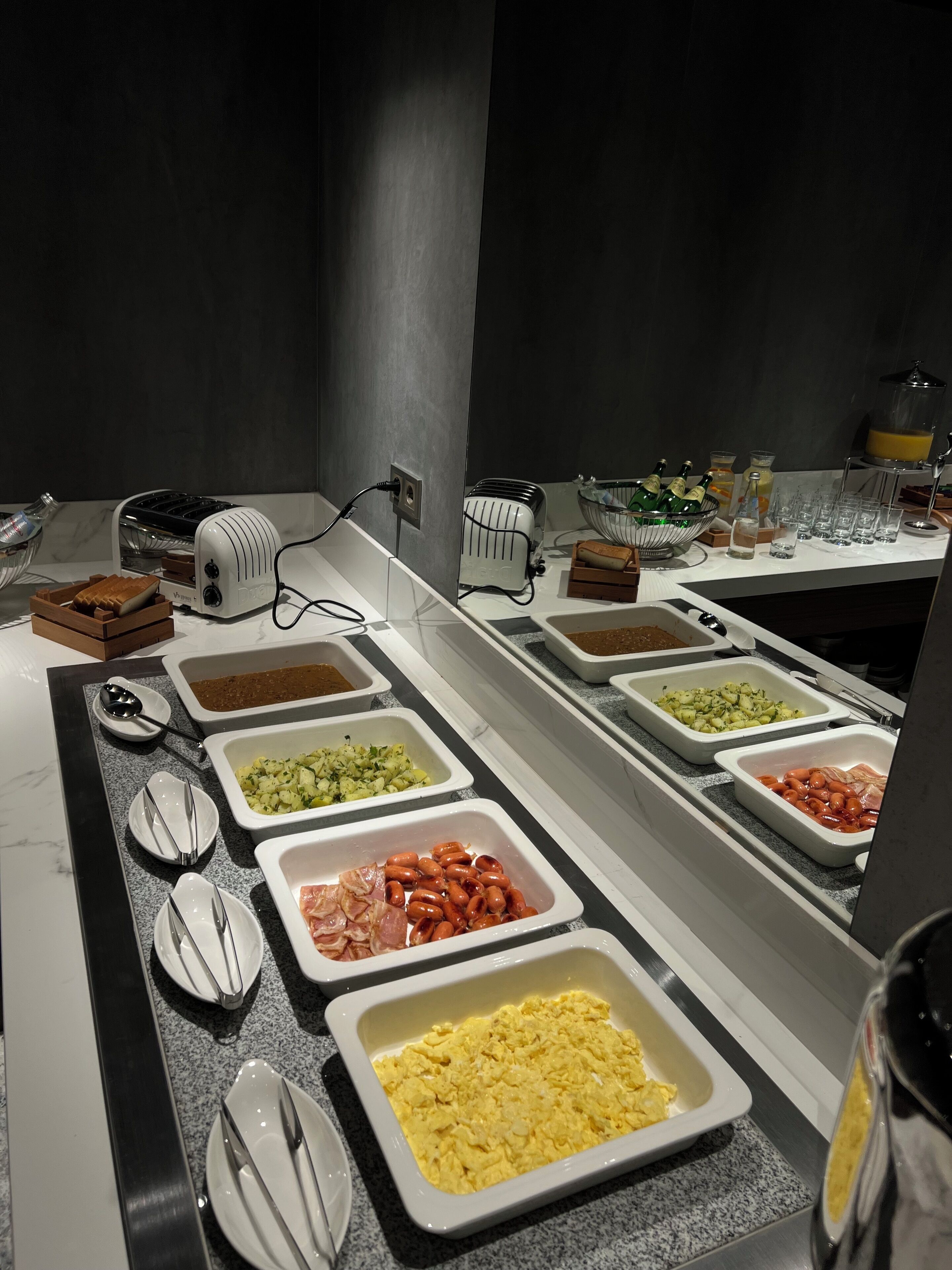 A buffet with various food options including eggs, sausages, and vegetables.