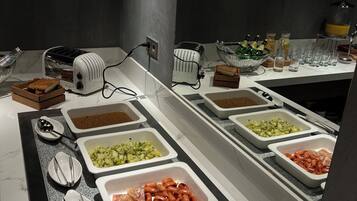 A buffet with various food options including eggs, sausages, and vegetables.