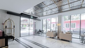 Eine moderne Lobby mit Marmorboden, zwei Sofas, einem Tisch und einem spiegel mit goldener Rahmung.