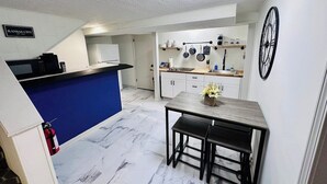 Una cucina compatta con una parete di colore blu, un'area pranzo con un tavolo in legno e un'isola cucina.