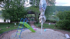 A playground with a slide, climbing structure, and sand area. - Four bedroom house with river view (Bihac)