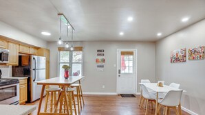 A modern kitchen with wooden cabinets, a stainless steel refrigerator, and a dining area with a white table and chairs. - Walk to Mall & Train Station! Philly Suburb Stay (Willow Grove)