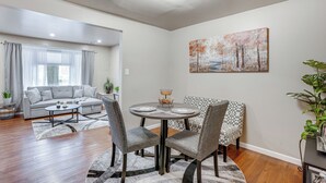 A modern living room with a dining area, featuring a sofa, chairs, a round table, and a painting on the wall. - Walk to Mall & Train Station! Philly Suburb Stay (Willow Grove)