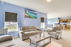 Relax in this inviting living room with a sofa, armchairs, and a coffee table, offering a view of the coastal landscape.