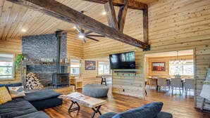 A spacious living area with a stone fireplace, comfortable seating, a television, and a dining area. - Fire Pit + Sauna: Inviting Utah Cabin (Duck Creek Village)