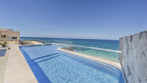 A swimming pool with clear blue water, a glass barrier, and a view of the ocean. - 4 BR PH Ocean View + Private Pool (Isla Mujeres)