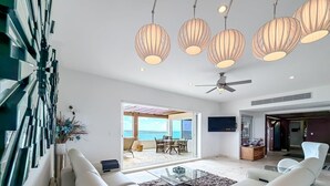 A modern living room with a sofa, a glass coffee table, and a ceiling fan. - 4 BR PH Ocean View + Private Pool (Isla Mujeres)