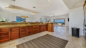 A spacious kitchen with a wooden island, a large window, and a view of the ocean. - 4 BR PH Ocean View + Private Pool (Isla Mujeres)
