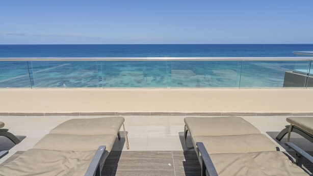 A poolside area with lounge chairs and a view of the ocean. - 4 BR PH Ocean View + Private Pool (Isla Mujeres)