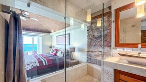 A modern bathroom with a glass shower enclosure, a marble backsplash, and a wooden vanity. - 4 BR PH Ocean View + Private Pool (Isla Mujeres)