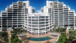 Um hotel com vários andares, pátio central, varandas e área de piscina.