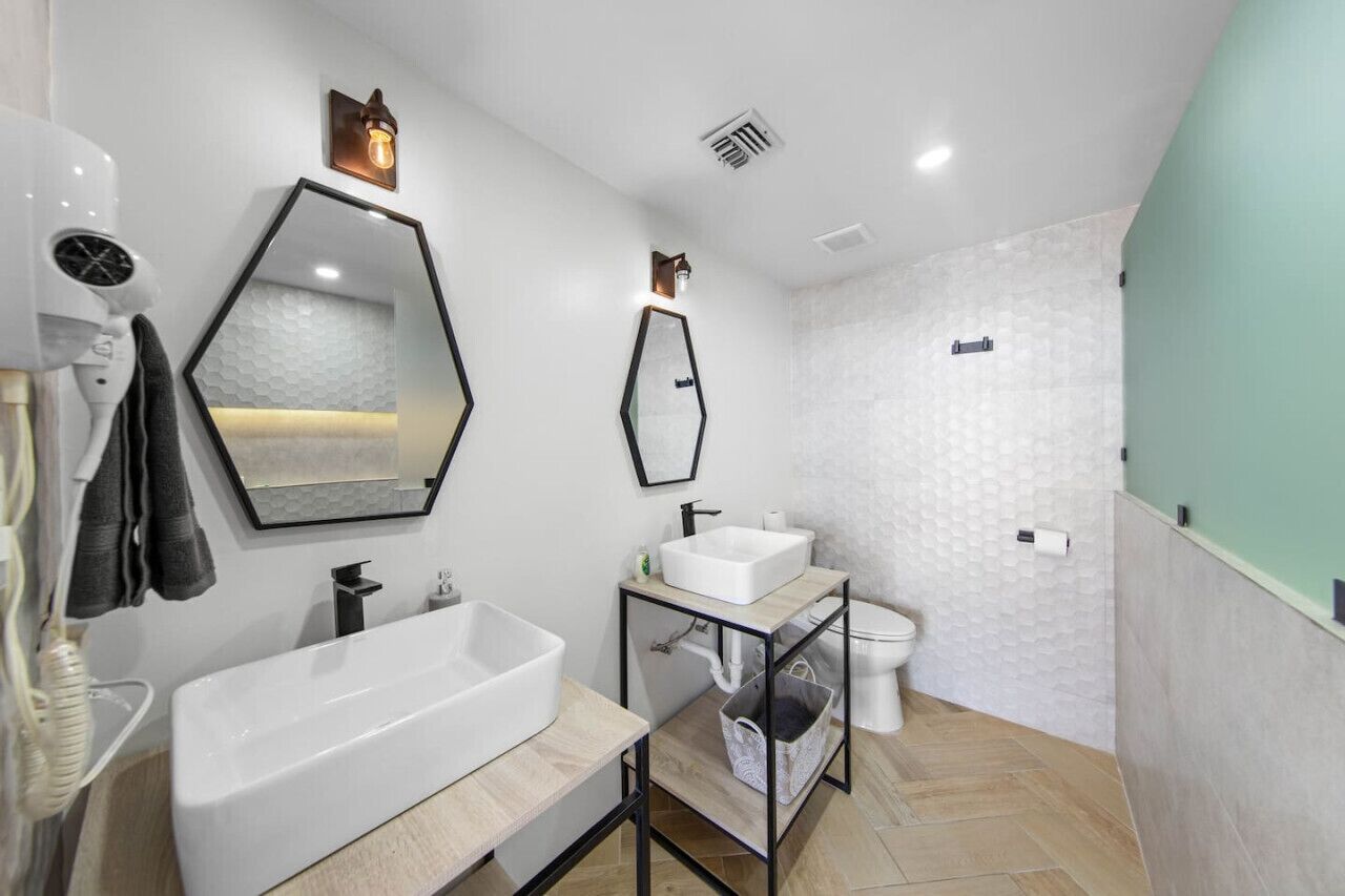 A modern bathroom with a large white sink, a mirror, and a toilet.