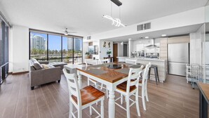 Um apartamento moderno com área de jantar, cozinha e uma grande janela com vista para a cidade.