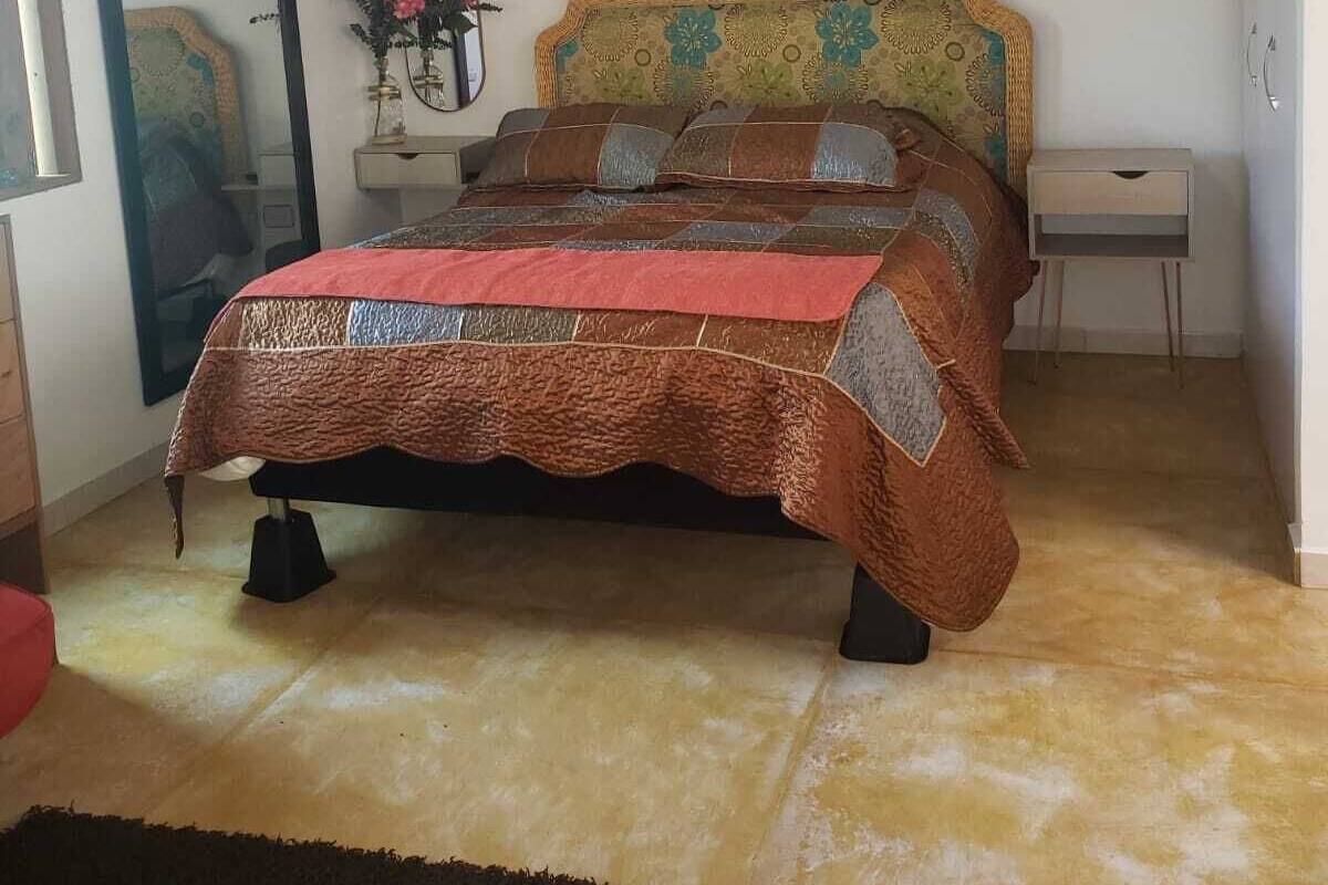 Un dormitorio con cama, mesita de noche, cómoda, espejo y candelabro.