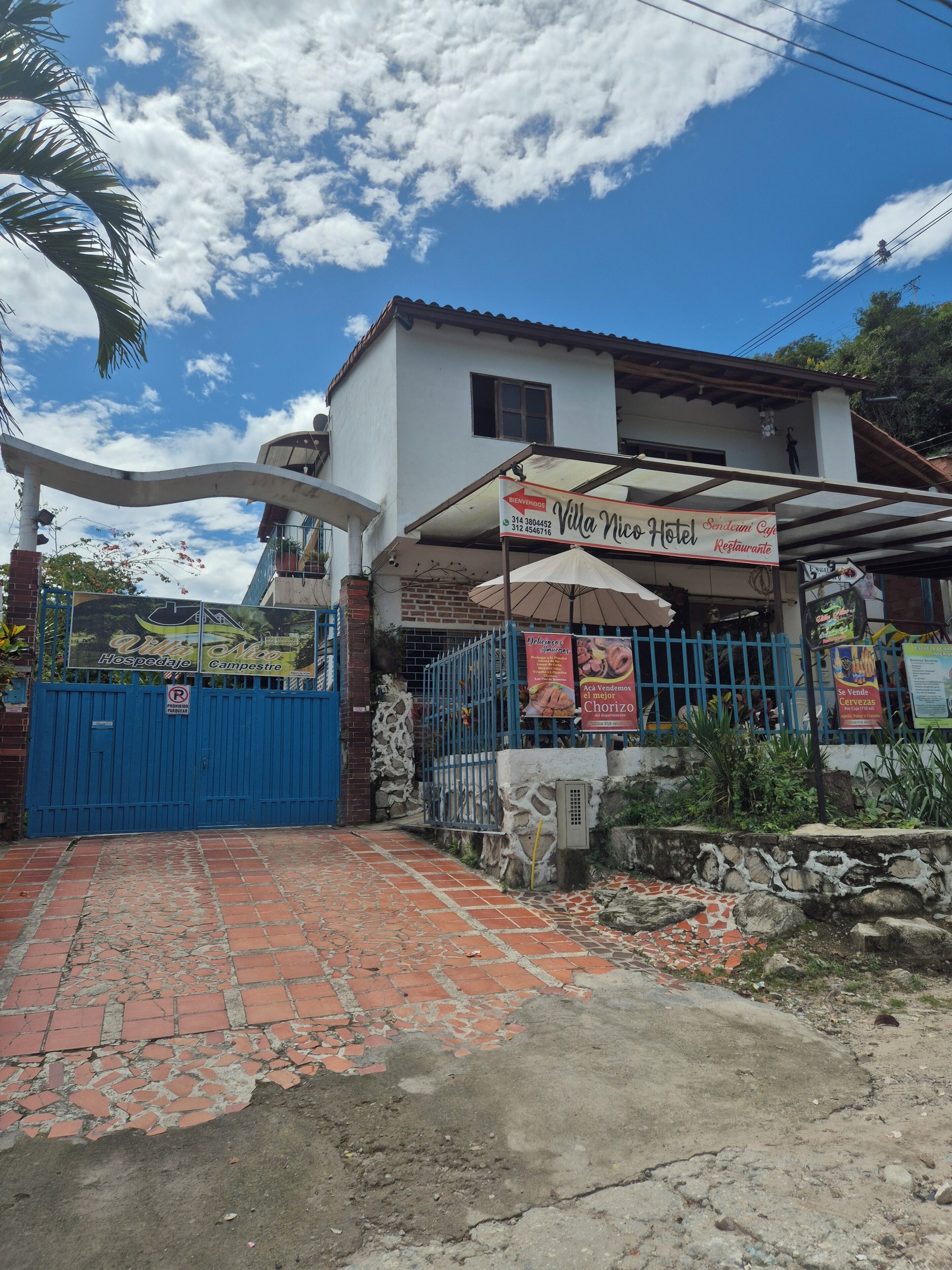 Villa Nico Hotel, mit blauem Tor, Schild und Steinmauer.