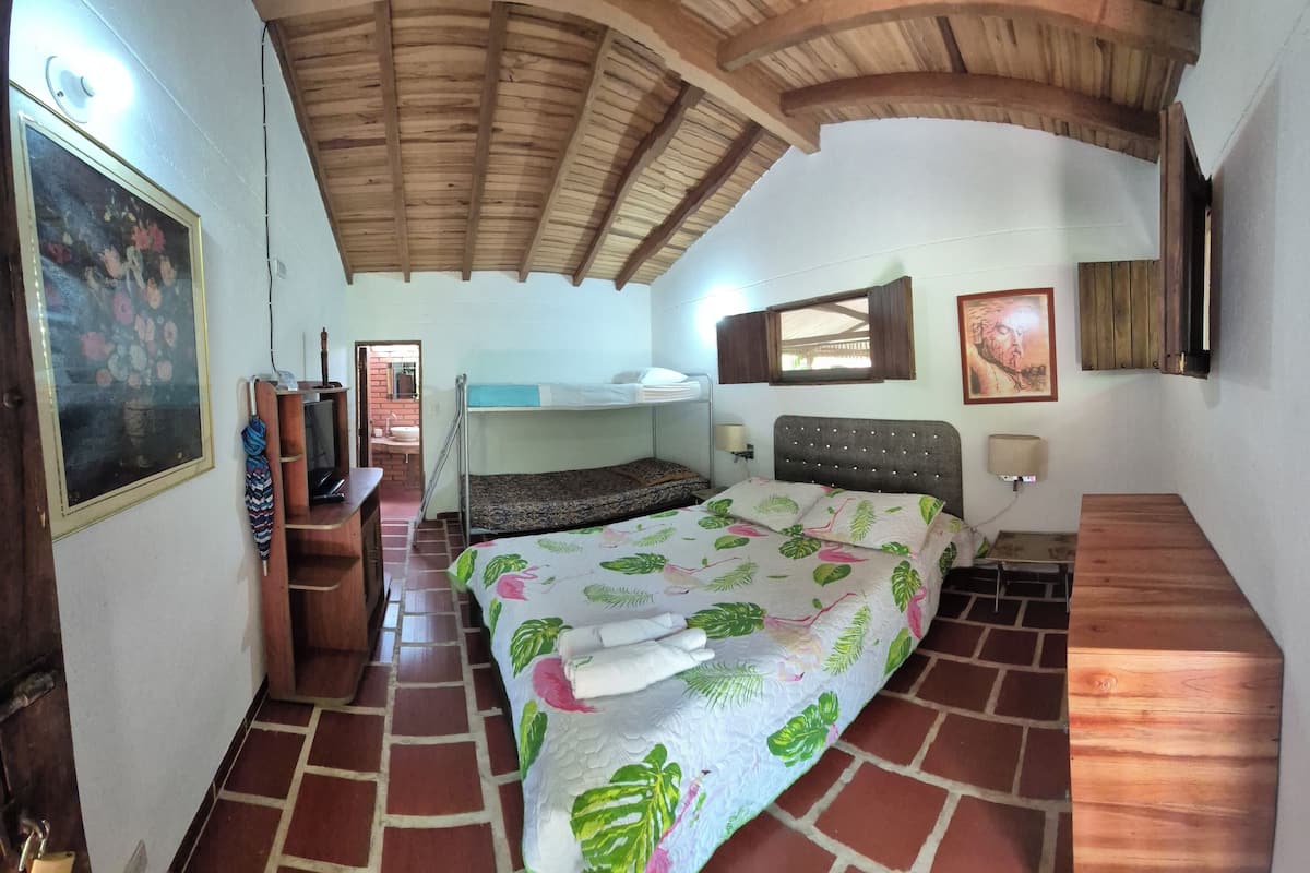 Una habitación con literas, un escritorio con silla, un espejo y un cuadro en la pared.