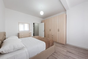A bedroom with a bed, a wardrobe, and a door leading to another room. - City Escape Apartment by PikHost (Shkodër)