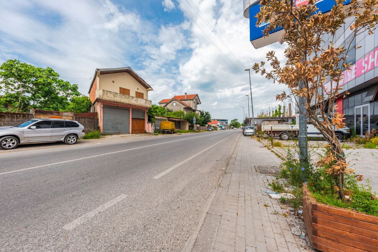 Eine Straße mit Gebäuden, einem parkenden Auto und einem Schild.