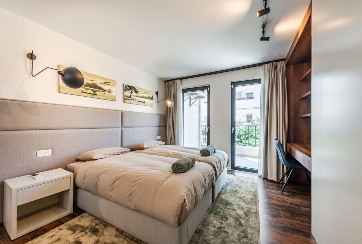 Una camera da letto moderna con un ampio letto, comodini, una scrivania e vista sull'esterno.