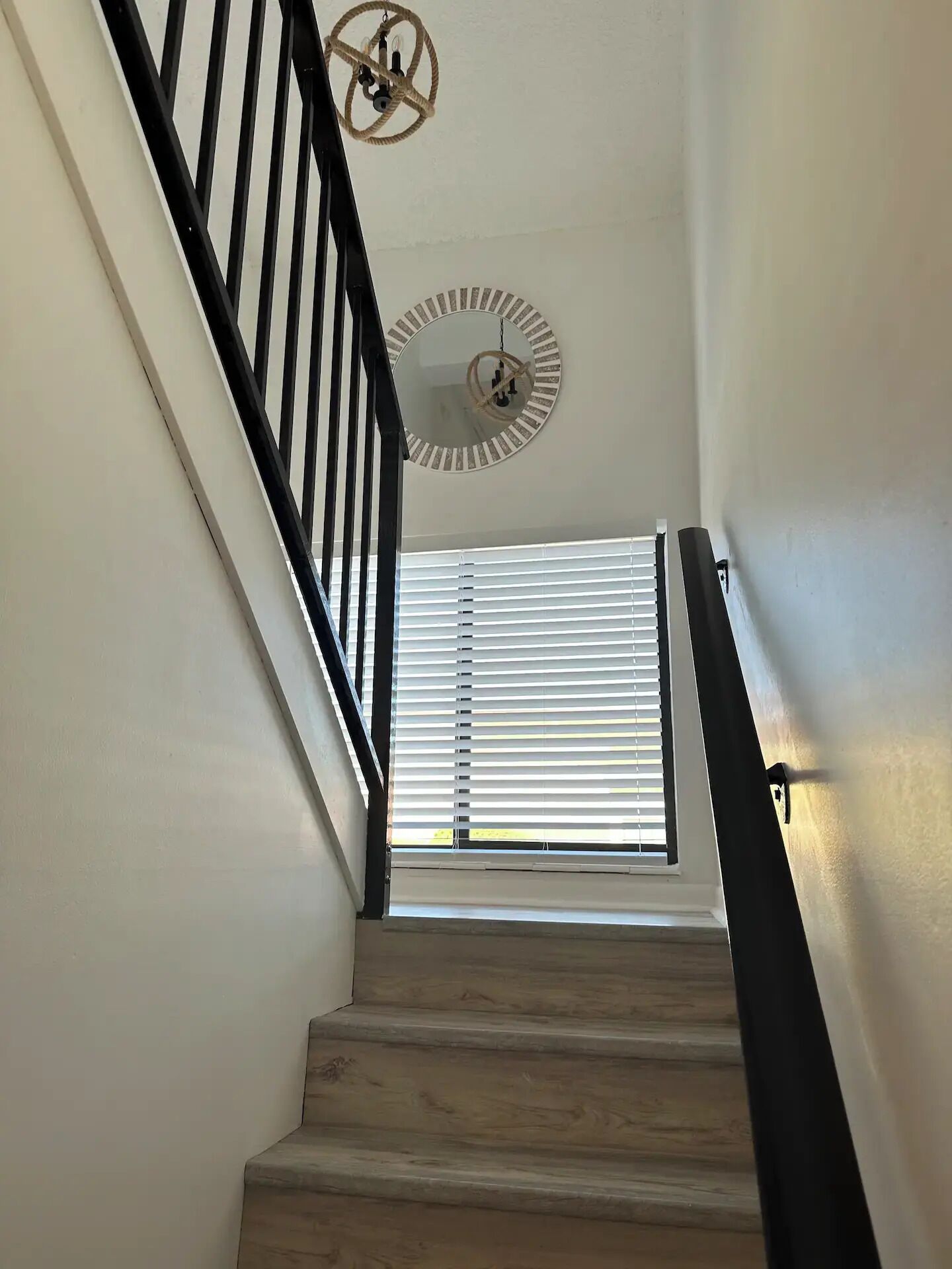 A staircase with wooden steps, black railings, and a ceiling fan.