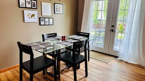 A dining area with a glass table, black chairs, and a wooden floor.