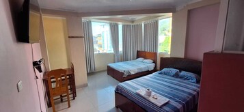 Habitación de hotel con dos camas, un televisor, un escritorio y una silla.
