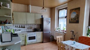 Una cocina con armarios de madera, un refrigerador, un lavamanos y una mesa de comedor con sillas.