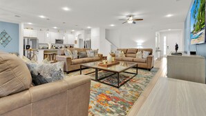 Ein modernes Wohnzimmer mit einer Couch, einem Couchtisch und einer Küche im Hintergrund.