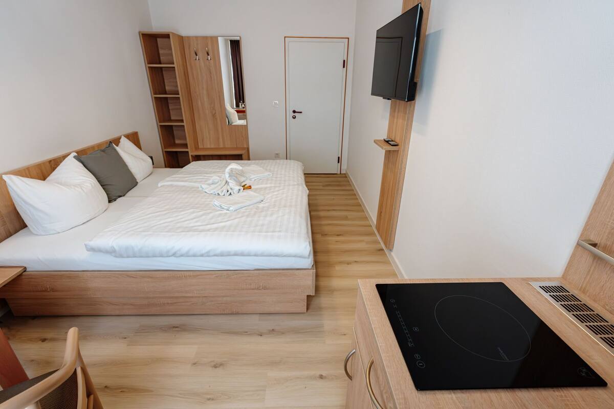 Une chambre à coucher comprenant un lit, une armoire en bois, une télévision et une cuisinière électrique encastrée.