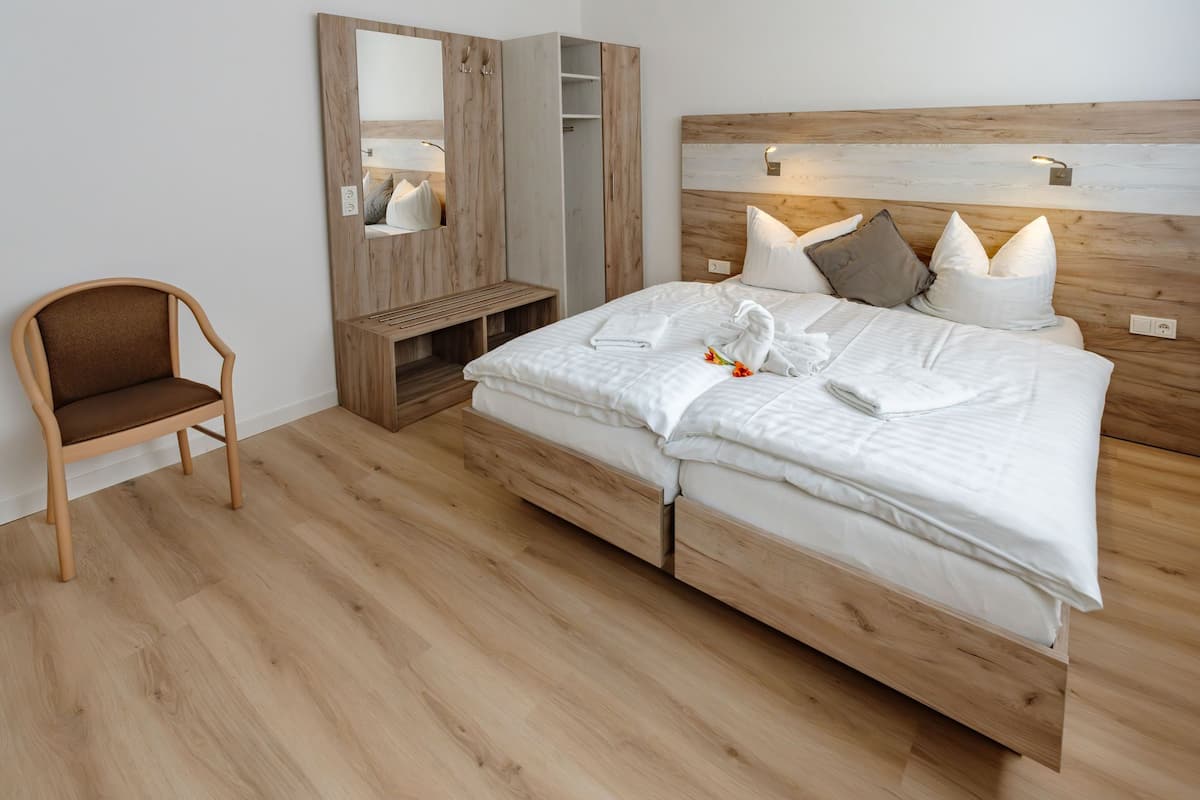 Une chambre à coucher avec un lit en bois, une chaise, une armoire et un miroir.