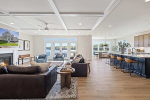 Un salón amplio con chimenea, un sofá grande y una zona de cocina con barra y taburetes altos.