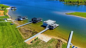 Vista aerea di una proprietà sul lago con barche ormeggiate, un pontile e un piccolo edificio.