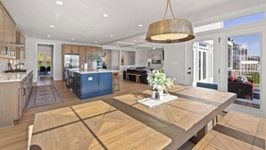 Un'ampia cucina con isola centrale, un'area pranzo con un grande tavolo in legno e vista all'esterno tramite porte vetrate.
