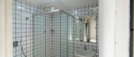 Un baño con cabina de ducha de vidrio, lavabo y espejo.