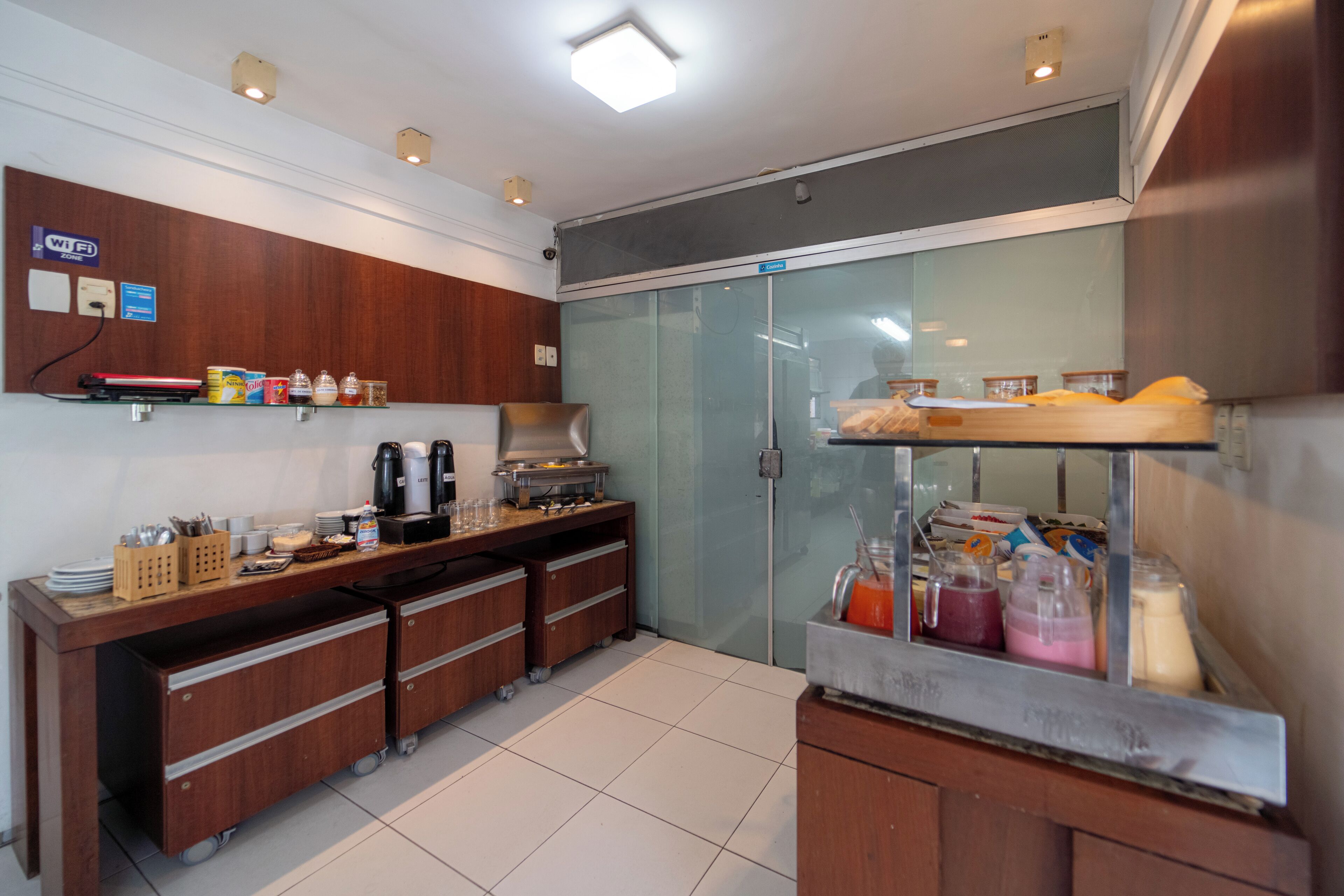 A kitchen with a coffee station, a refrigerator, and a counter with various food items.