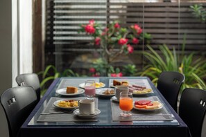 Mesa de café da manhã com pratos de comida, um copo de suco de laranja e uma xícara.