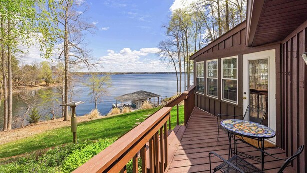 A wooden deck with a table and chairs overlooking a lake. - Lakefront Lake Anna with Views, Dock, Fire Pit (Bumpass)