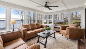 A sunroom with a large window, a ceiling fan, and leather furniture. - Lakefront Lake Anna with Views, Dock, Fire Pit (Bumpass)