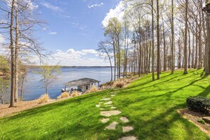 A lakeside property with a grassy pathway leading to a wooden structure. - Lakefront Lake Anna with Views, Dock, Fire Pit (Bumpass)
