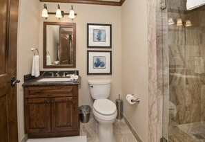 A bathroom with a wooden vanity, a white toilet, and a shower area.