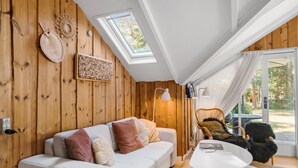 Une pièce chaleureuse avec un mur en bois, un canapé blanc, une table ronde et une chaise.