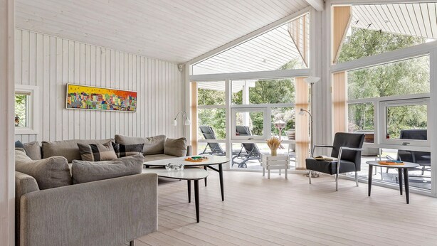 Ein geräumiges Wohnzimmer mit großem Fenster, einer Couch, einem Couchtisch und einem Sessel.
