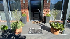 A modern building entrance with a brick facade, large windows, and potted plants. - Spacious Bayside Elwood Home. Walk to the beach, the botanical gardens, cafes.. (Elwood)