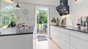 Eine moderne Küche mit einer großen Kochinsel, Edelstahlgeräten und Pendelleuchten.