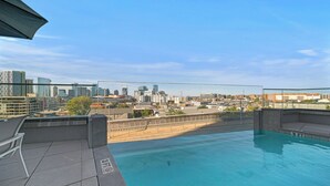 A rooftop pool with a city skyline view, a covered seating area, and a concrete deck. - The Hidden Hills Suite The Gulch (Nashville)